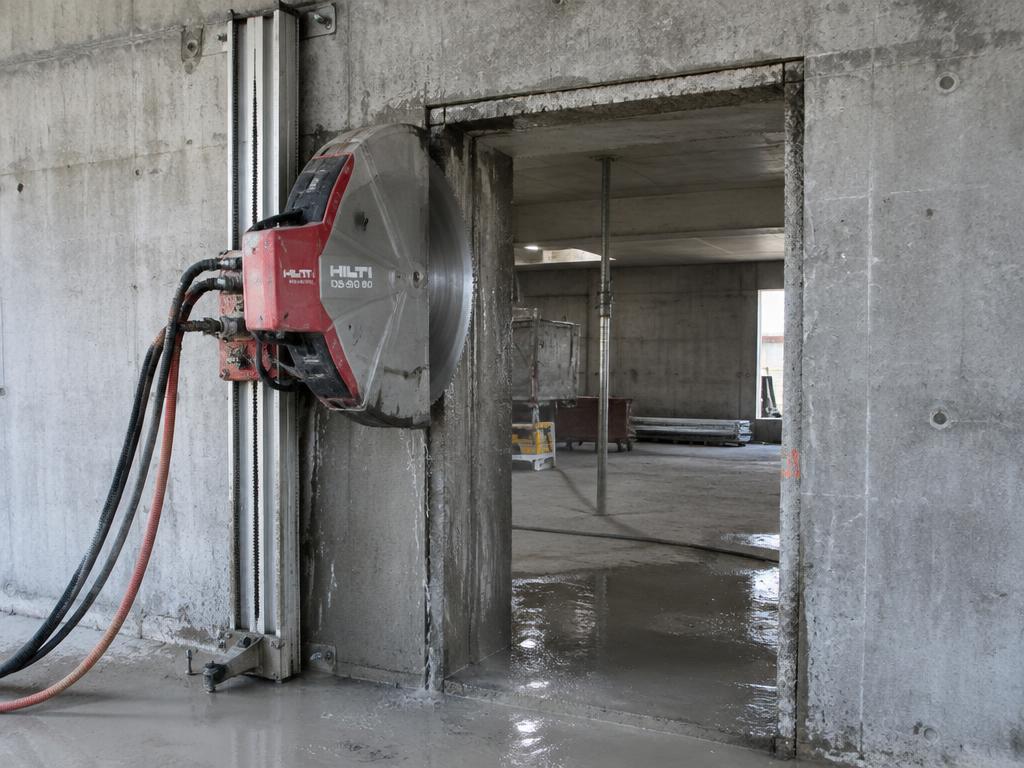 Track-mounted wall saw cutting a doorway opening in a concrete wall